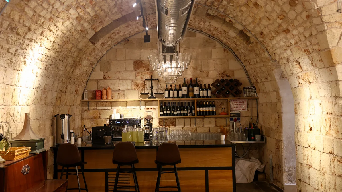 חלל קמרונות אבן תת קרקעי עם בר עץ, כיסאות גבוהים ותאורה חמה