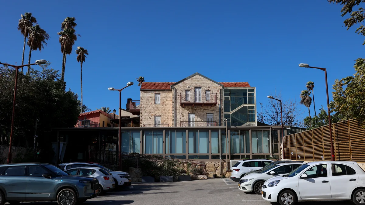 חזית מבנה האבן ההיסטורי עם חלונות זכוכית גדולים וחניון צמוד